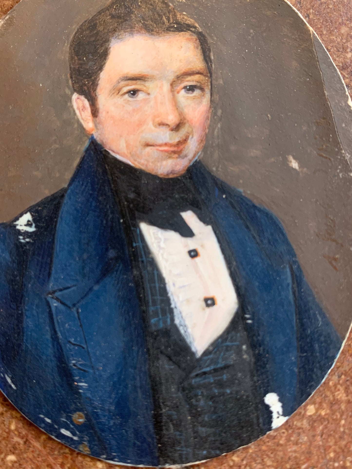 A miniature portrait of an elegant man in a black tie and pleated shirt with jewel buttons, dated 1833.