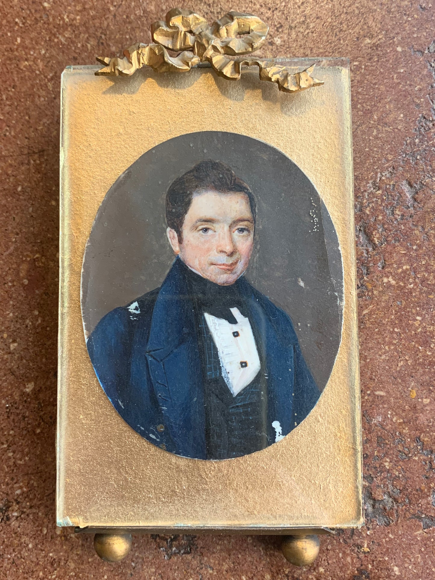 A miniature portrait of an elegant man in a black tie and pleated shirt with jewel buttons, dated 1833.