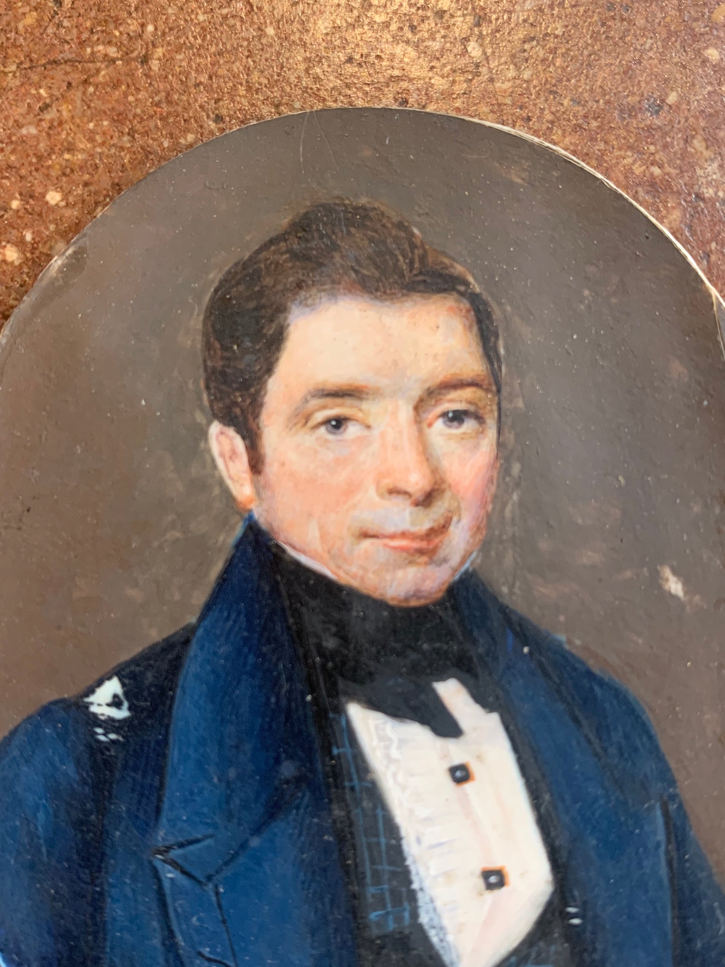 A miniature portrait of an elegant man in a black tie and pleated shirt with jewel buttons, dated 1833.