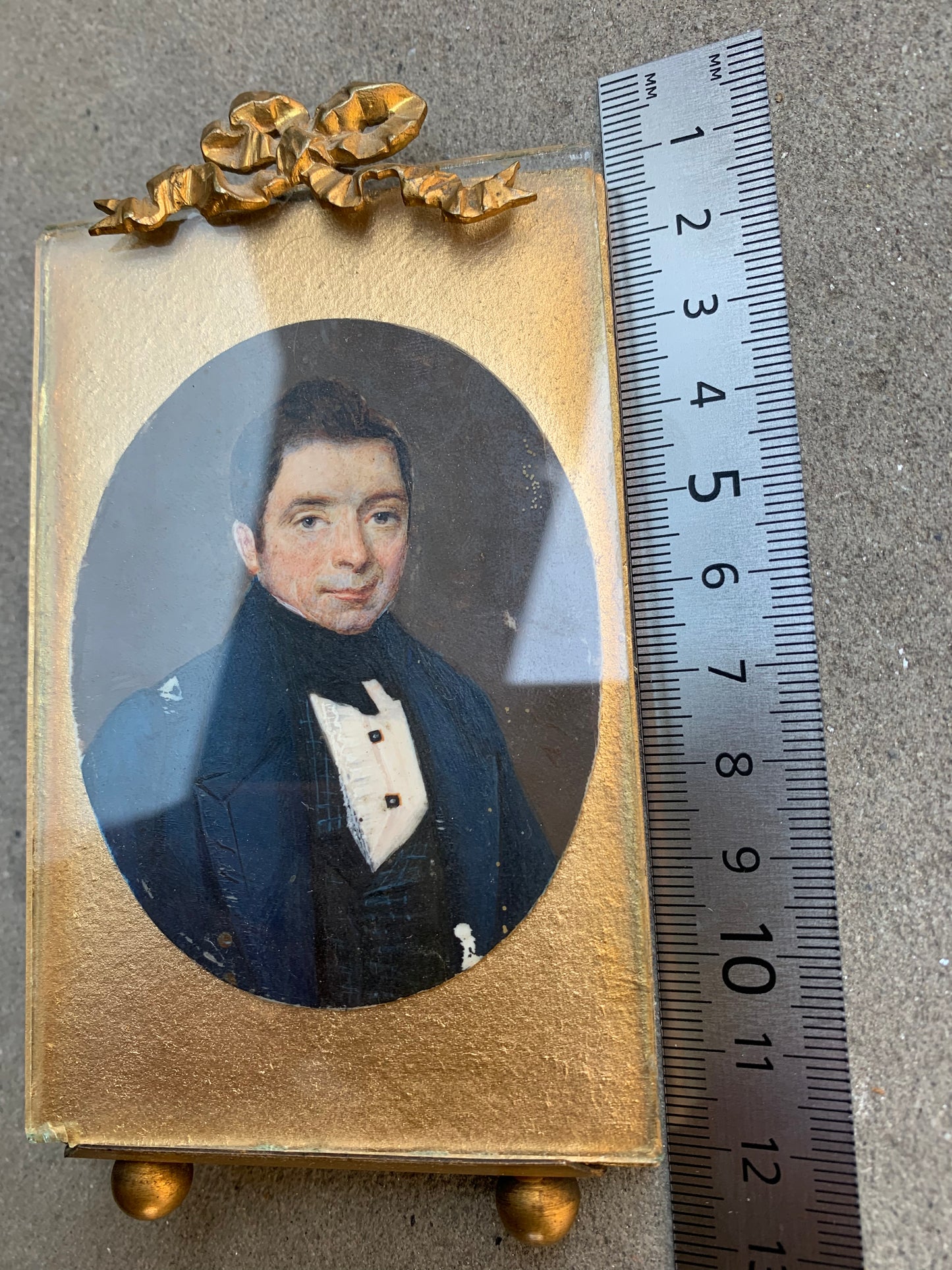 A miniature portrait of an elegant man in a black tie and pleated shirt with jewel buttons, dated 1833.