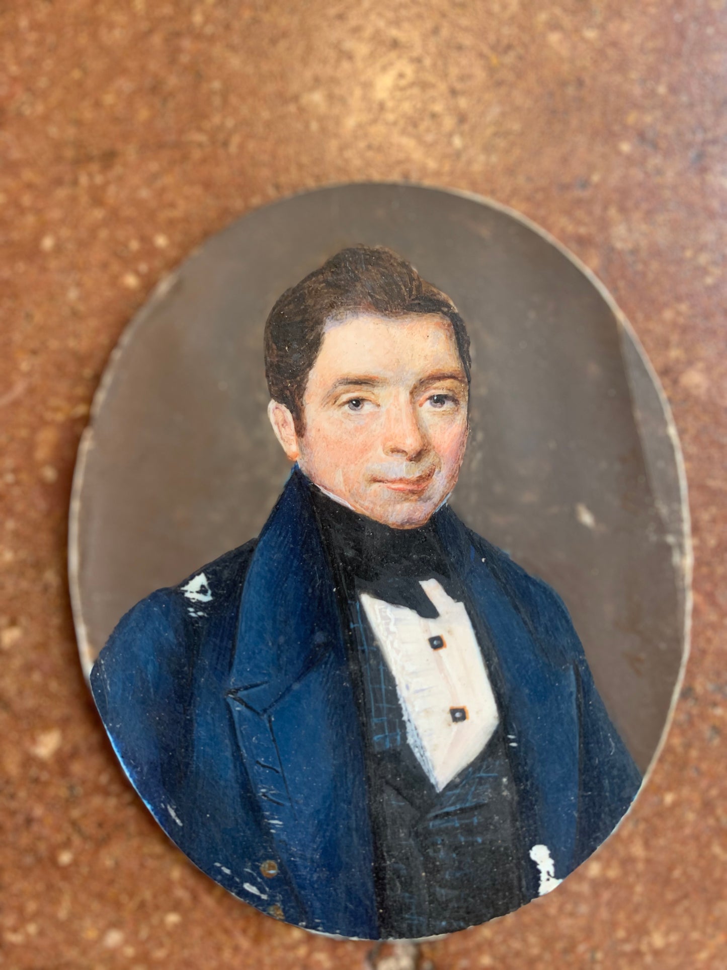 A miniature portrait of an elegant man in a black tie and pleated shirt with jewel buttons, dated 1833.